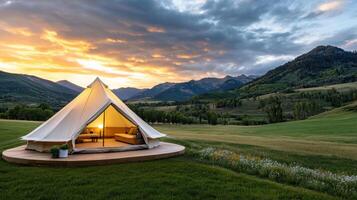 A tent in the middle of a field with mountains in the background photo