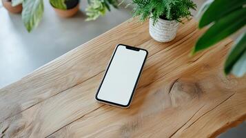 Mockup of smartphone on wooden table with potted plant photo