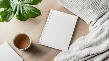 Blank notebook, coffee and plant on wooden table photo