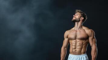 A shirtless man standing in front of a black background photo