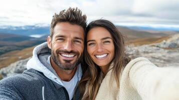 A man and woman taking a selfie on a mountain photo