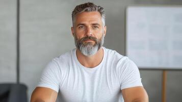 confident man with beard and short hair is sitting modern office setting, exuding photo