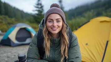 Cozy camper enjoying nature with warm smile, surrounded by tents and greenery photo