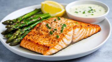 Salmon and asparagus on a plate with a side of sauce photo