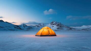A tent is lit up in the snow at night photo