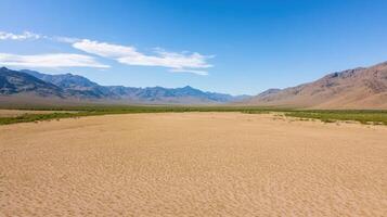 An aerial view of a desert landscape with mountains in the background photo