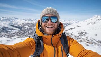 joyful person orange jacket and sunglasses smiles while taking selfie snowy mountain landscape photo