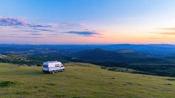 A camper van parked on a hill at sunset photo