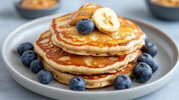A stack of pancakes topped with blueberries and peanut butter photo