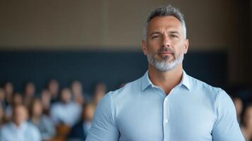 A man with a beard standing in front of a classroom photo