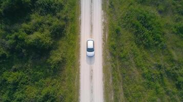 Aerial view of a car driving on a dirt road in the forest photo