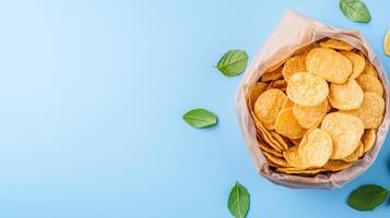 Baked potato chips in paper bag on blue background photo