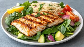 Grilled fish served bed of fresh greens with quinoa and colorful vegetables creates healthy meal photo