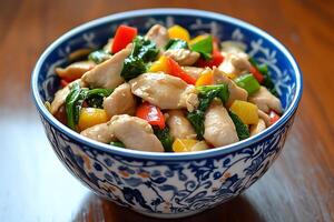 Delicious Chicken Stir-Fry with Bell Peppers and Spinach in a Blue and White Bowl. photo