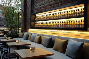 Stylish Outdoor Restaurant Patio with Brick Wall and Illuminated Wine Bottle Display. The inviting seating area features a modern design and warm lighting. photo