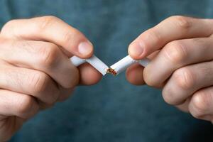 Determined individual breaking a cigarette in half symbolizing a commitment to quitting smoking and embracing a healthier lifestyle photo