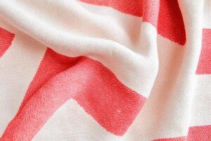 Close-up view of a textured blush and red striped textile pattern showcasing folds and intricate details creating a warm and inviting look photo