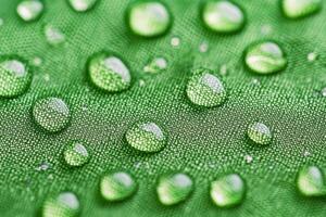 Close-up of textured green outerwear fabric showcases rain droplets, emphasizing durability and outdoor readiness for adventure photo
