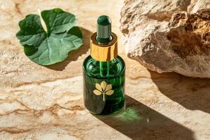 Green cosmetic serum bottle with gold elements standing on marble surface with leaf and stone photo