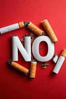 Broken cigarettes forming the word no on red background photo