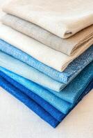 Stack of linen fabric swatches in different shades of blue and beige showing linen texture photo