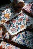 Hand-painted floral textiles arranged on a surface with a roll in the background photo