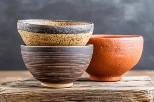Ceramic bowls stacked on a wooden surface showcasing unique textures and colors, perfect for serving food or decorative purposes, kitchenware concept photo