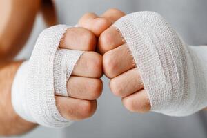 Boxer wrapping hands with white boxing bandages getting ready for training photo