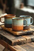 Three Rustic Ceramic Mugs on a Wooden Table photo