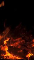 Flickering flames create a warm and inviting atmosphere in a fireplace, casting soft light on nearby surfaces. The glowing embers provide comfort on a cold night. Vertical footage video