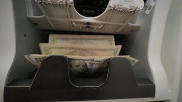 Close-up of a money counting machine processing US dollar banknotes. Represents financial transactions, currency handling, banking, and cash management in a business context video