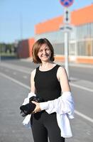 A woman with a confident smile and sunglasses is featured in front of a modern architectural element. photo