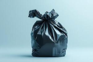 A black garbage bag tied at the top, resting on a light blue background. photo