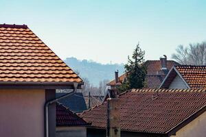 A scenic view of terracotta rooftops with a hazy city skyline in the background, exuding warmth. photo