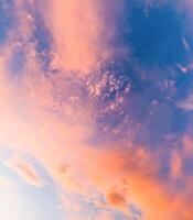 A breathtaking sky filled with dynamic orange and blue clouds, illuminated by the warm glow of the setting sun, creating a peaceful yet dramatic atmosphere. photo