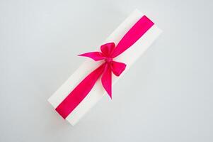 Rectangular gift box with pink ribbon on white background photo