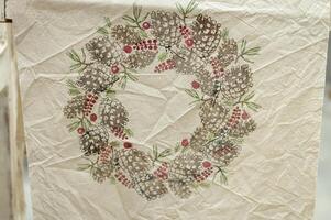 Rustic pine cone and berry wreath on textured fabric background photo