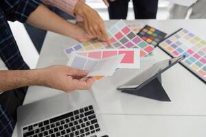 Collaboration and Creative Review. Diverse team discussing color palettes and design elements in a modern workspace. photo