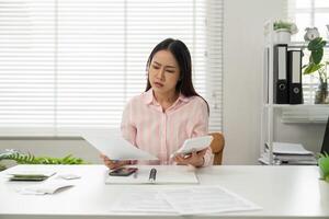 Home Office Productivity and Problem Solving. A woman analyzes documents while looking concerned, demonstrating efficient home office management. photo