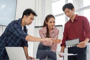 Syncing Ideas and Projects for Optimal Outcomes. Team members review design mockups and discuss project alignment in a creative workspace, emphasizing effective collaboration. photo