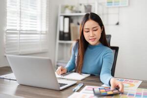 Creative Process and Color Selection. A designer contemplating color choices while working on her laptop. photo