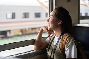 Reflections and Travel Dreams. A woman gazes out of a train window, smiling at the world passing by. photo