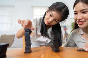 Joy and Fun. The playful interaction between a mother and her daughter as they build and compete in a stacking game. photo