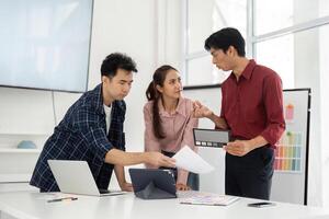 Collaboration and Creativity. A team of three professionals engaged in a vibrant brainstorming session, reviewing color palettes on digital devices. photo