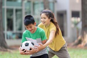 Play and Exercise. A girl playfully competes with a boy for control of a soccer ball in a park. photo