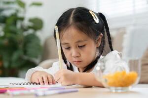 Back to School and Learning Fun. A focused girl studying on a notebook at home, practicing her writing skills. photo