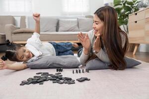 Family Bonding and Playtime. A mother and daughter share a joyful moment while playing a game on the floor, strengthening their connection through laughter. photo