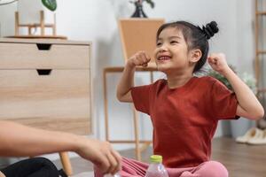 Strength and Joyful Play. A little girl showcasing her muscle with pride during a playful exercise routine. photo