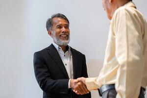 Smiling male businessman in a suit shaking hands during a successful deal negotiation photo