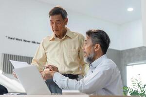 Seasoned businessmen discussing project updates while examining documents in a bright office environment photo